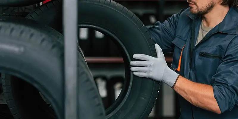 Technician inspecting a tire on a rack in an auto shop, preparing tires for installation