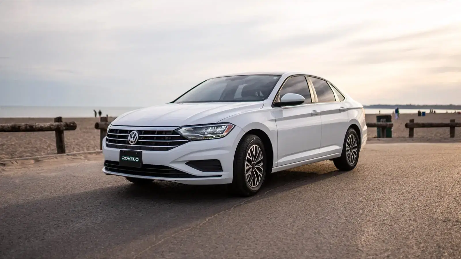 Volkswagen Jetta parked on beachside road, showcasing its stylish design and all season tires for smooth driving.