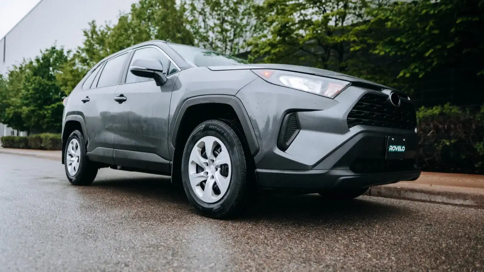SUV with Rovelo Instinct S.V. tires parked on a rainy road, showcasing sleek design and modern features.