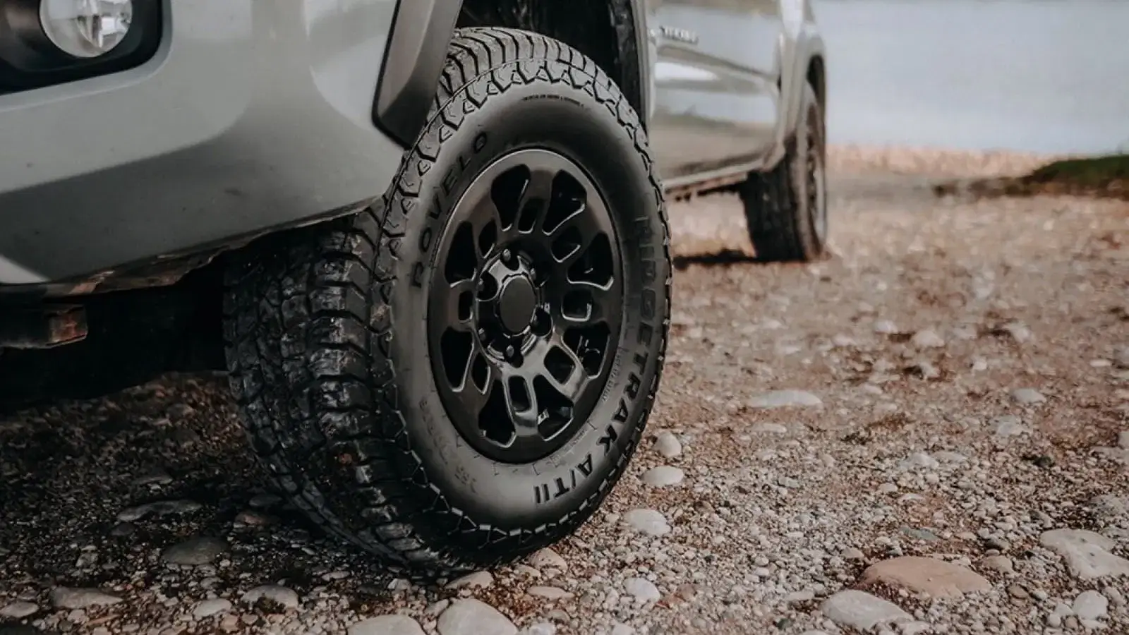Tire close-up of Rovelo RidgeTrac all terrain tire on SUV navigating rocky terrain.
