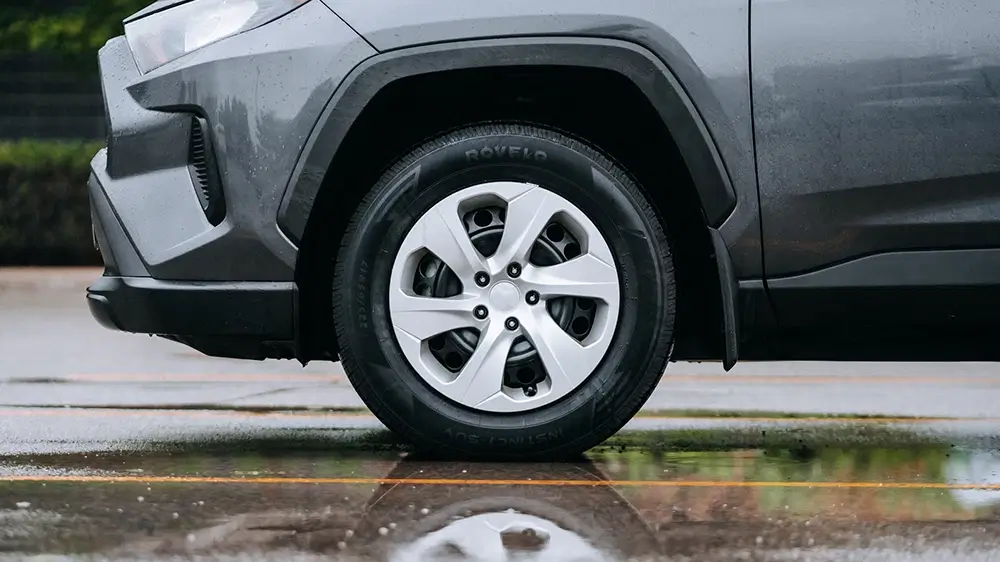 Gray SUV with all season tires parked on a wet road, showcasing the tread design for traction.
