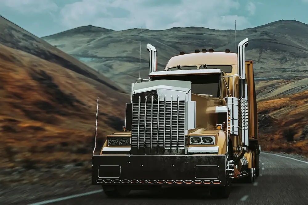 Large truck with chrome grille and all terrain tires driving on winding mountain road